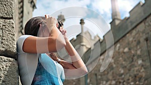 Smiling female professional photographer taking photo of medieval castle using camera