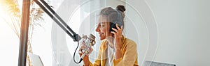 Smiling female radio host recording and broadcasting her podcast from homemade studio