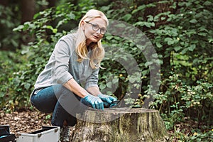 smiling female scientist in latex gloves sitting with tweezers and magnifier