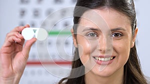 Smiling female showing contact lens at camera, patient recommendation, choice