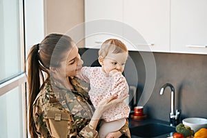 Smiling female soldier holding a pretty girl in her arms