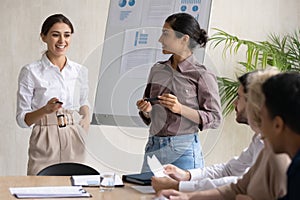 Smiling female speakers make whiteboard presentation at briefing