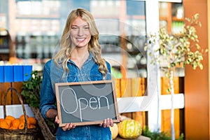 Smiling female staff holding open sign board in super market