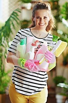 Smiling female in striped shirt in sunny day housecleaning