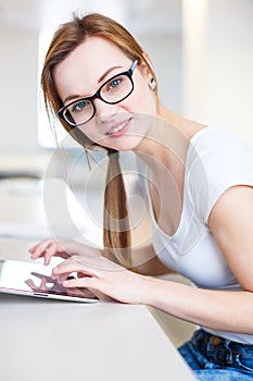 Smiling female student/ businesswoman using her tablet computer