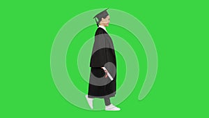 Smiling female student in graduation robe walking with her diploma on a Green Screen, Chroma Key.