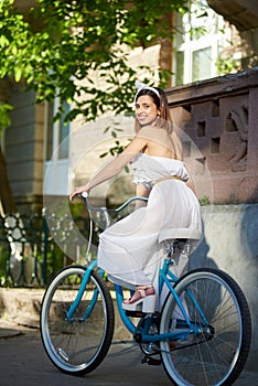 Smiling female in sunny day on bicycle at city street