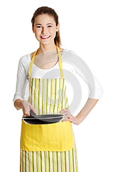 Smiling female teen with a frying pan.