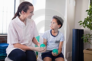 Smiling female therapist looking at boy holding stress balls