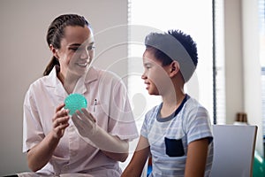 Smiling female therapist showing stress ball to boy