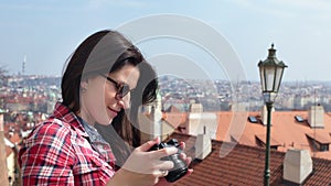 Smiling female tourist taking photo city panorama using camera enjoying vacation side view