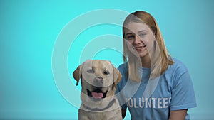 Smiling female volunteer with cute pedigreed dog looking at camera, help animals