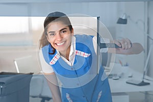 Smiling Female Worker Cleaning Glass Window With Squeegee