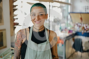 Smiling female worker standing on background of print machine in design studio and looks camera