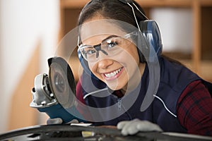 smiling female worker using angle grinder