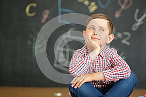 A smiling first grader sits on the background of a school board.