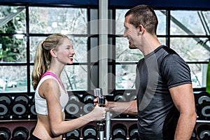 Smiling fit couple lifting dumbbells