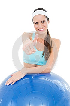 Smiling fit woman with fitness ball gesturing thumbs up