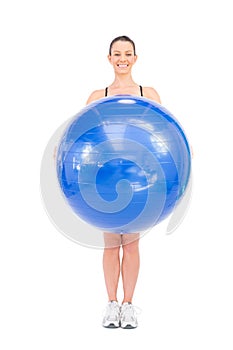 Smiling fit woman holding exercise ball in front of her