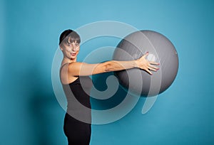 Smiling fit woman holding fitness ball stretching body muscles