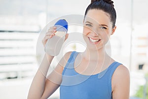 Smiling fit woman holding plastic flask