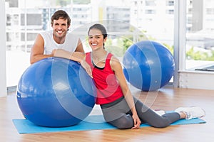 Smiling fit young couple with exercise ball at gym