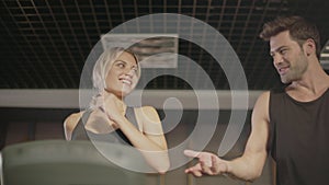 Smiling fitness couple talking on treadmill machine in gym club