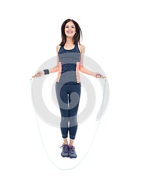 Smiling fitness woman jumping with skipping rope