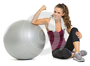 Smiling fitness woman sitting near fitness ball