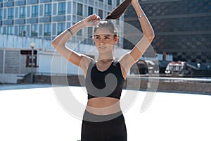 Smiling fitness woman in training clothes standing on a street during morning jog