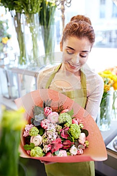 Smiling florist woman with bunch at flower shop