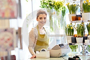 Smiling florist woman at flower shop cashbox