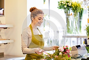 Smiling florist woman making bunch at flower shop