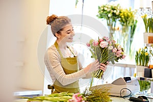 Smiling florist woman making bunch at flower shop