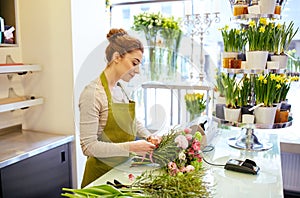 Smiling florist woman making bunch at flower shop