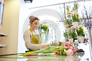 Smiling florist woman making bunch at flower shop