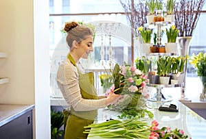 Smiling florist woman making bunch at flower shop