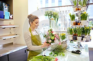 Smiling florist woman making bunch at flower shop