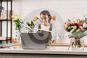 Smiling flower shop owner working on laptop