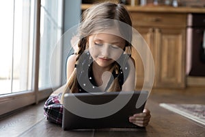 Smiling focused gen Z girl using app on tablet computer