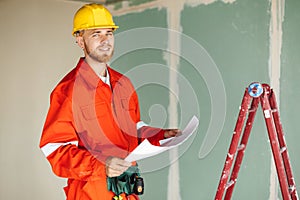 Smiling foreman in orange work clothes and yellow hardhat happil photo