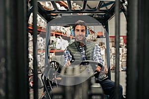 Smiling forklift driver working on the floor of a warehouse