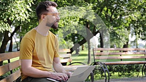 Smiling freelancer in glasses using laptop in park