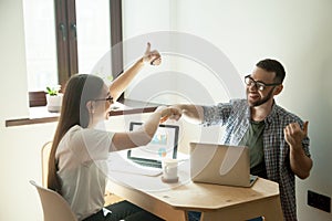 Smiling freelancers giving fists bump and showing thumbs up