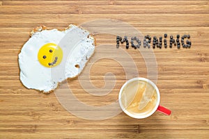 Smiling fried egg lying on a wooden cutting board with morning inscription near it. Classic Breakfast concept.