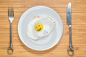 Smiling fried egg lying on a wooden cutting board with morning inscription near it. Classic Breakfast concept.