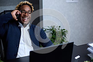 Smiling friendly African man talking on phone in office