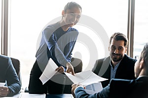 Smiling friendly businesswoman giving handout material to employee at meeting photo