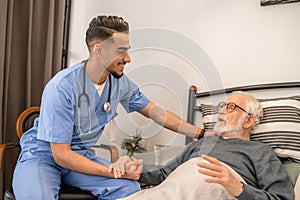 Smiling friendly doctor visiting a bedridden patient