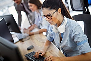 Smiling friendly female call-center agent with headset working on support hotline in the office